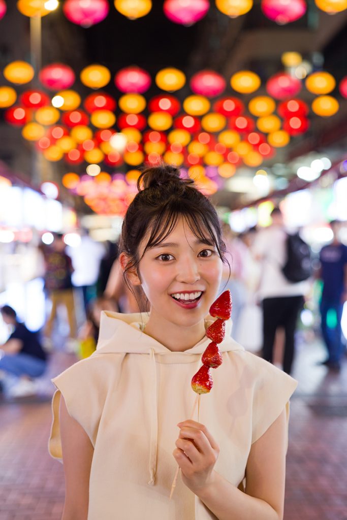 乃木坂46阪口珠美1st写真集より香港のナイトマーケットでいちご飴を食べているかわいらしいカット